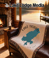 Tapestry with Lake Tiorati, New York map design draped over leather sofa by fireplace.
