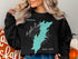 Black sweatshirt with a teal map of Trout Lake, New York, and compass rose graphic.
