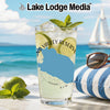 Tall glass of a beverage with limes and mint on a beach with Lake Lodge Media logo.