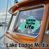 "Little Turtle Life" sticker on a wooden boat window with "Lake Lodge Media" text.