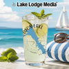 Glass with drink, lime, mint, sunglasses, and sailboat on beach background.