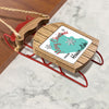 Wooden sled ornament with red runners and a tag saying Merry Christmas from Hauser Lake.