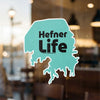 Turquoise sticker with black text "Hefner LIFE" and "Lake Lodge Media LLC".