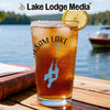 Glass with iced tea, lemon, and "Lake Lodge Media" logo on a lake background.