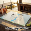 A rectangular glass cutting board with a blue Lake Leelanau map design rests on a wooden dock.