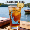 Glass of iced tea with blue map outline and compass, set on a wooden table.
