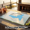 A tempered glass cutting board featuring a map of Lake Gregory, California rests on an outdoor wooden bar.