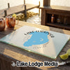 A glass cutting board featuring a blue map of Lake Istokpoga, Florida, rests on a wooden dock.