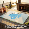 A glass cutting board featuring a blue map of Indian Lake, Ohio rests on an outdoor wooden bar.
