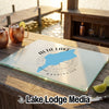 A glass cutting board featuring a blue map of Alta Lake, Washington rests on a wooden dock.