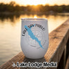 A white insulated tumbler featuring a blue map of Lake San Pablo rests on a wooden dock at sunset.