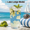 Glass with "Lake Lodge Media" logo, limes, mint, and bubbles on a beach background.