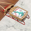 Christmas ornament on a wooden sleigh shaped sled with text "Merry Christmas From West Okoboji".