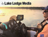 Man in boat with life vest and sunglasses on lake at sunset, "Lake Lodge Media" text.