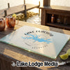 Rectangular glass cutting board featuring a blue map of Lake Ouachita, Arkansas, on a wooden outdoor bar.