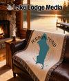Woven blanket with Jordan Pond map and compass design on a leather sofa.