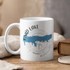 White mug with blue Enid Lake map and compass design, steaming.