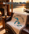 Woven blanket with Great Lakes map and compass design on a leather couch.