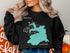 Black sweatshirt with a teal map outline of Big Lake, Arizona.