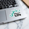 Turquoise Monroe Life sticker shaped like a lake on a laptop keyboard.
