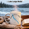 White mug with Skaneateles Lake compass design, steam rising, by a window.
