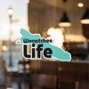 Wenatchee Life sticker on a window with blurred background and interior lights.
