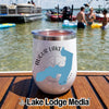A white stainless steel tumbler featuring a blue lake silhouette sits on a wooden boat deck overlooking a sunny lake with people and boats.