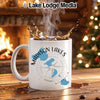 White mug with "Madison Lakes Wisconsin" and compass design, by fireplace.