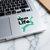 Turquoise "Raw Life" sticker on a silver laptop keyboard.