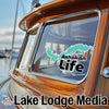 Green Ashokan Life sticker on a wooden boat window, with Lake Lodge Media text.