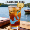 Iced tea in a glass with a map design and lemon slice by a lake.