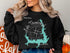 Black sweatshirt with turquoise Lake Thunderbird map and compass graphic.