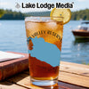 Glass of iced tea with lemon on a table by a lake, "Lake Lodge Media" text.