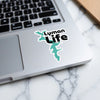 Sticker with turquoise lake outline and black "Lyman Life" text on a laptop.