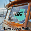 Teal outline with "Emerald Life" in bold black text on wood boat window.