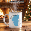 White mug with Lake Tahoe map design, steaming coffee, fireplace, and Christmas tree.