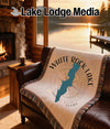 Woven blanket with "White Rock Lake Texas" map design on a leather couch.