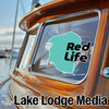 Turquoise "Red Life" sticker on a boat window with "Lake Lodge Media" text below.