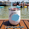 A white Crater Lake Oregon insulated tumbler sitting on a wooden boat deck with lake and swimmers in the background.