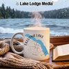 White mug with Eklutna Lake, Alaska map and compass design on window sill.