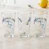 Three clear pint glasses with a blue lake map and compass design.