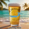 Glass of beer with "Lake Crescent" text and compass on beach with ocean background.