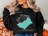Black sweatshirt with teal map of Lake Winnipesaukee, New Hampshire.
