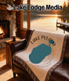 Cream blanket with Lake Pulaski, Minnesota map and text on leather sofa.