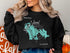 Black sweatshirt with "Beautiful Marco Island Florida" map design and people silhouettes.