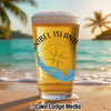 Beer glass with Sanibel Island, Florida map and compass on beach at sunset.