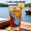 Glass with iced drink, featuring Stanley Draper Lake map, lemon slice, and "Lake Lodge Media" logo.