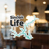 Sinclair Life sticker on glass with teal lake outline and copyright Lake Lodge Media LLC.