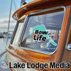 Teal "Bowv Life" sticker on a wooden boat window with "Lake Lodge Media" text below.