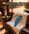 Black Lake Idaho map design woven blanket on leather couch with lake view.